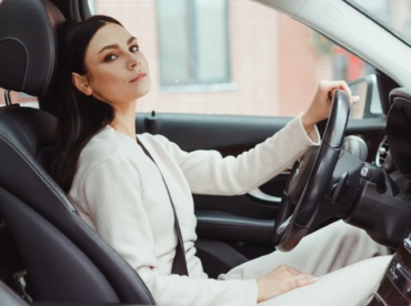 Photo of happy young woman sitting inside her new car. Concept for car rental