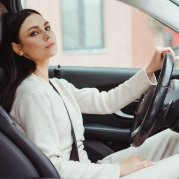 Photo of happy young woman sitting inside her new car. Concept for car rental