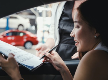 Woman signs the document in order to pick up the car from the car rental.